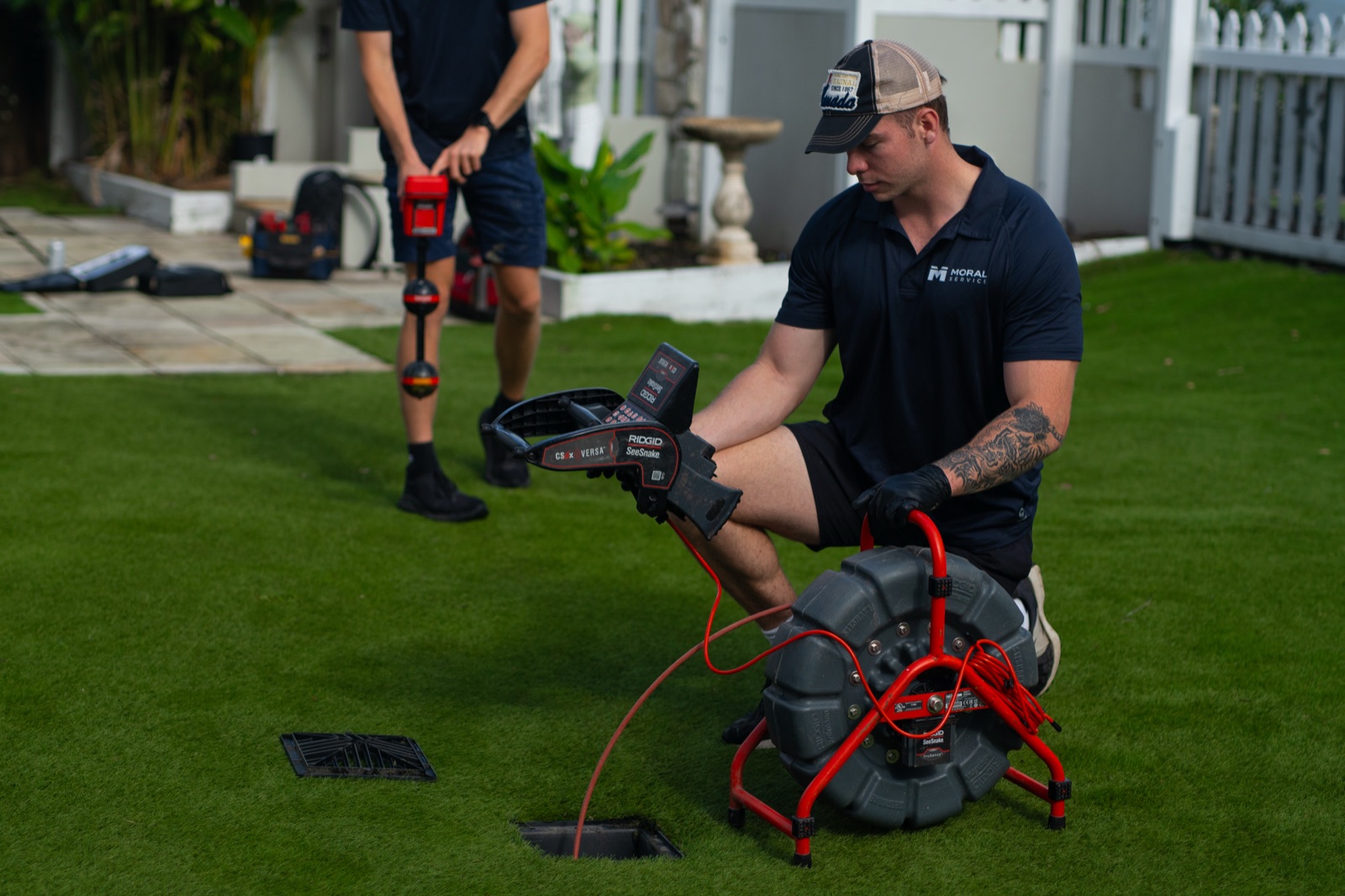A Moral Service plumber feeding a CCTV drain camera into a backyard drain at a Gold Coast home