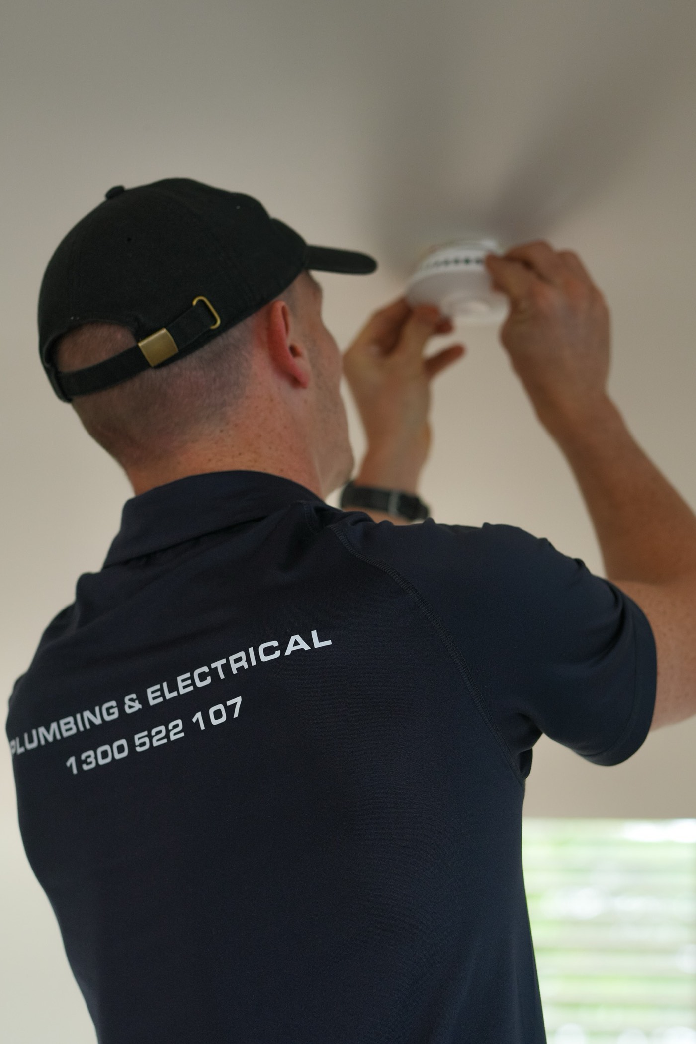 A Moral Service electrician fitting a smoke alarm to the ceiling