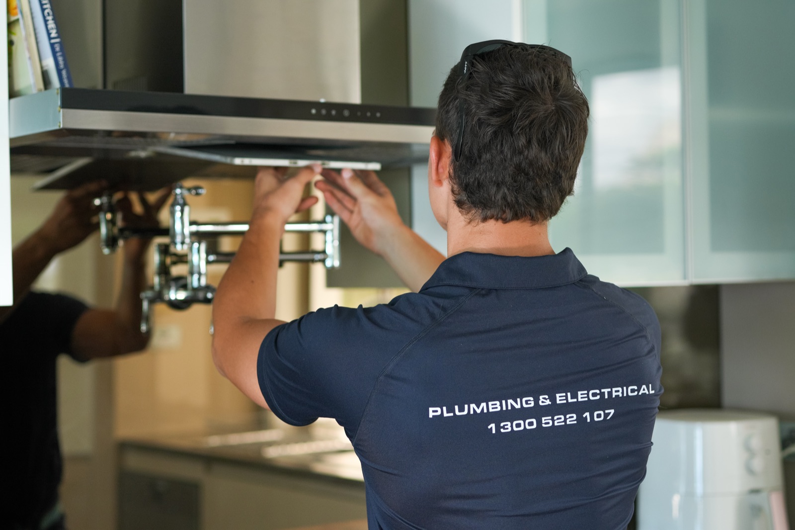 A Moral Service electrician fitting off a kitchen rangehood in a new kitchen