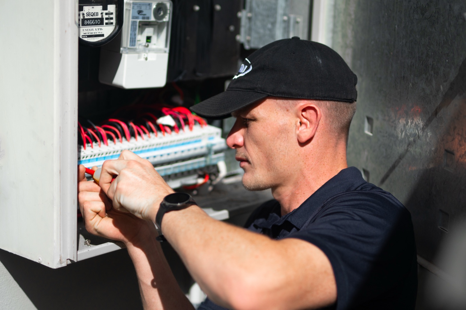A Moral Service electrician working on a home switchboard with an insulated screwdriver